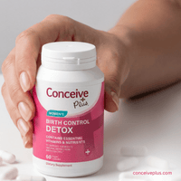 Hand holding a Conceive Plus Women's Birth Control Detox supplement bottle against a neutral background.