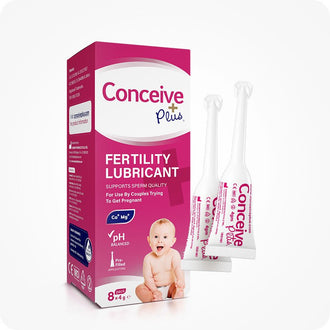 Conceive Plus Fertility Lubricant (8x4g Pre-filled Applicators) box shown upright with bold pink and white branding, featuring a smiling baby image on front; three slim, white pre-filled applicators displayed to right, each labeled with product details for individual use.
