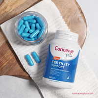 Fertility support supplement with blue capsules on a wooden surface