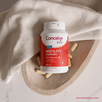 Conceive Plus motility support supplement bottle on a wooden tray with beige cloth