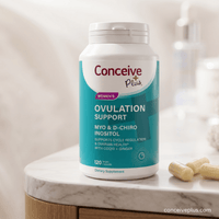 Supplement bottle labeled 'Conceive Plus Women's Ovulation Support' on a marble surface.