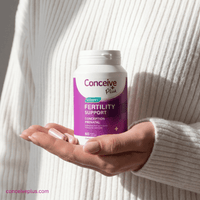 Person holding a bottle of Conceive Plus Fertility Support supplement.